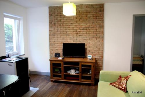 a living room with a tv and a brick wall at Apartament Anna in Srebrna Góra