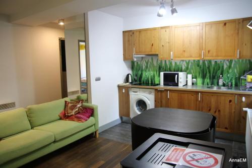 a living room with a green couch and a kitchen at Apartament Anna in Srebrna Góra
