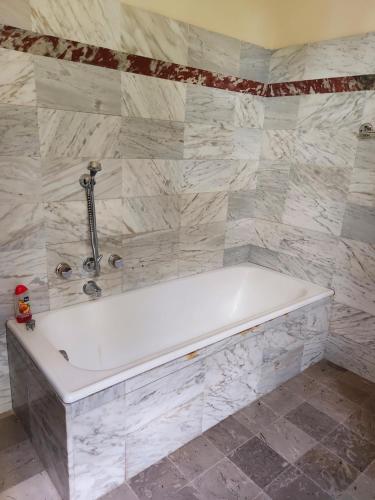y baño con bañera blanca y paredes de mármol. en Villa Ca' di Monte, en Scopeti
