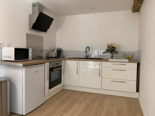a white kitchen with white cabinets and appliances at Le Bois Dormans in Dormans