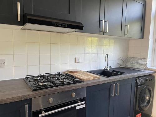 a kitchen with a stove top oven next to a sink at 4 Bed: 5mins frm Wembley Stadium in London