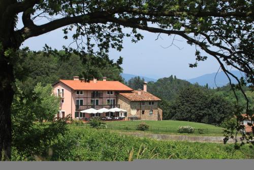 een groot huis op een heuvel naast een veld bij Agriturismo Scacciapensieri in Buttrio