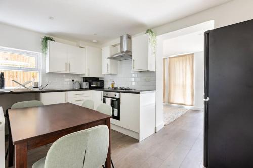 a kitchen with white cabinets and a table and chairs at Gorgeous London Town House Sleeps up to 8 in London