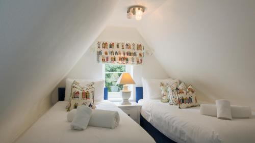 two white beds in a attic room with a window at The Cobblers, Luxury Coastal House for 16 in Wells next the Sea