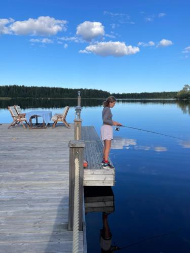 a young girl standing on a dock holding a fishing pole at Timber house with private beach and boat including. in Njurundabommen