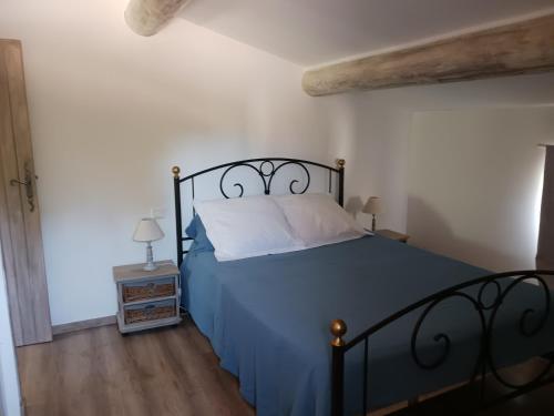 a bedroom with a bed with a blue comforter at Mas de la Chêneraie Blanche, Maison de vacances avec piscine en Luberon in Roussillon