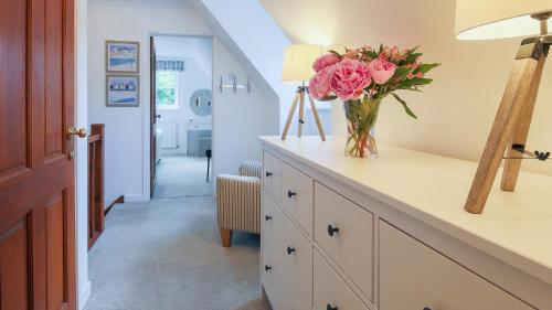 un vase de fleurs roses sur un comptoir dans un couloir dans l'établissement Cobblers Cottage, Wells Next The Sea, à Wells-next-the-Sea