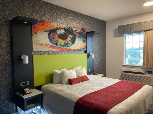 een slaapkamer met een bed met een schilderij aan de muur bij Lindsay Inn in Lindsay
