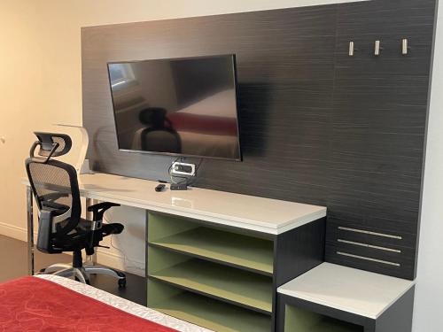 a bedroom with a desk with a monitor on a wall at Lindsay Inn in Lindsay