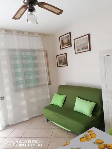 a green couch in a living room with a ceiling fan at Hausemaremma 1 camera in Follonica