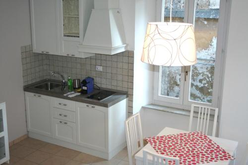 cocina con armarios blancos, mesa y lámpara en Appartamenti Urbevetus, en Orvieto