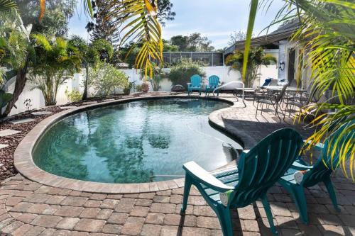 een zwembad met stoelen en een tafel en een huis bij Coral Cottage pool/firepit a 2 bed 2 bth sleeps 6 in Palm Harbor