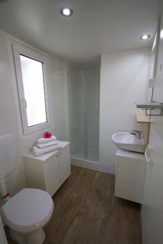 a white bathroom with a toilet and a sink at Camping Santin in Cavallino-Treporti