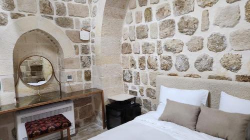 a bedroom with a stone wall with a bed and a mirror at Ana Talia House in Mardin