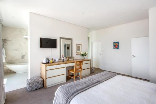 a bedroom with a bed and a desk and a sink at Far Horizons Camps Bay in Cape Town
