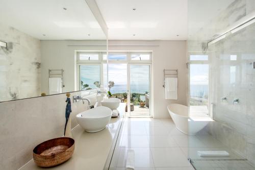 a bathroom with three sinks and two mirrors at Far Horizons Camps Bay in Cape Town