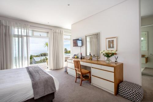 a bedroom with a desk and a bed and a window at Far Horizons Camps Bay in Cape Town
