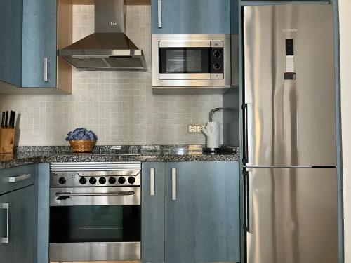 a kitchen with blue cabinets and a stainless steel refrigerator at Sea&Harbour Puerto del Carmen in Puerto del Carmen