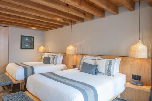 two beds in a room with wooden walls and beams at El Lugar del que te hable Hotel Boutique in Valle de Bravo