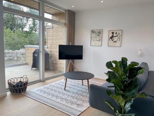 uma sala de estar com uma televisão, uma mesa e uma planta em Nybygget hus i Svaneke tæt på klipper, skov og hav em Svaneke