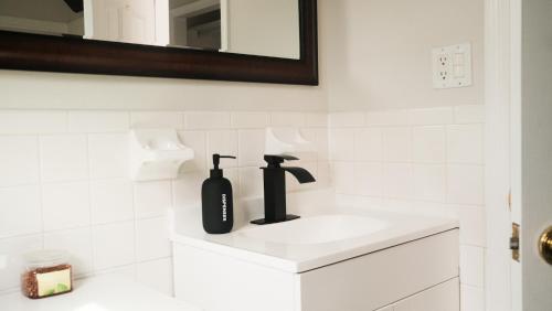 a white bathroom with a black bottle on a sink at King Bed & Fenced Yard - Floyd's Freedom- in Alexandria