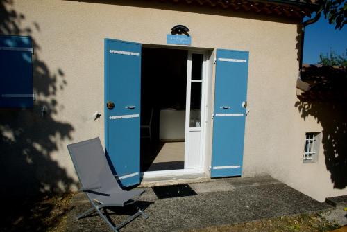 a blue door with a chair in front of a building at Nid douillet - LES FARGETTES - superbe vue - charmante petite maison avec jardin - 2 pièces à Privas in Privas