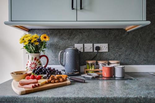 a kitchen counter with a cutting board with fruits and vegetables at Brimmond Homes - nr to Univ, Hospitals, o2 Apollo, PLAB & 7 mins to City Centre - Stylish, Modern & Secure 2 Bed, 2 Bath Apt with Allocated Free Parking in Manchester