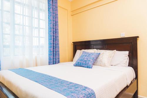 1 dormitorio con 1 cama con cortinas azules y ventana en Haven Air BnB Embu en Embu