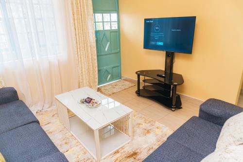 een woonkamer met een blauwe bank en een tv bij Haven Air BnB Embu in Embu