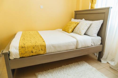 Una cama con manta amarilla y almohadas. en Haven Air BnB Embu en Embu