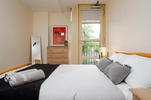 una camera da letto con un grande letto bianco e una finestra di Brimmond Homes - nr to Univ, Hospitals, o2 Apollo, PLAB & 7 mins to City Centre - Stylish, Modern & Secure 2 Bed, 2 Bath Apt with Allocated Free Parking a Manchester