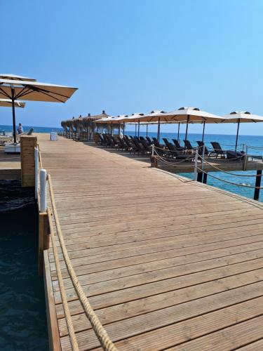 a wooden pier with chairs and umbrellas on the beach at Boheme B6 Sunrise Beach in Kalecik
