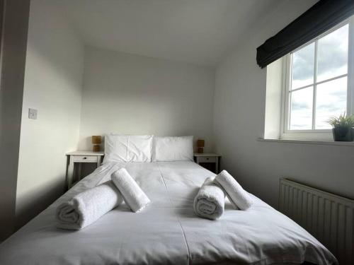 a white bed with two pillows and a window at Chaplin House in Sileby