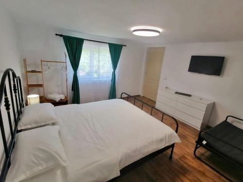 a bedroom with a white bed and a television at Casa M.A.R.A in Corbeni