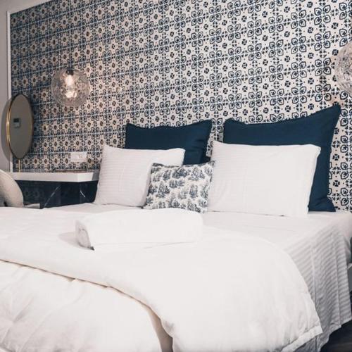 a bedroom with two white beds and a wall at BLUE LUXURY SUITES in Preveza