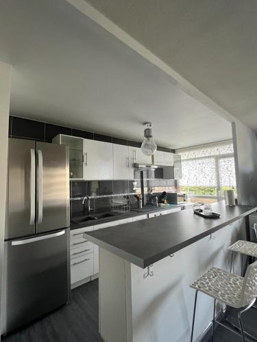 une cuisine avec un réfrigérateur en acier inoxydable et des armoires blanches dans l'établissement Modern'Habitat B&B, à Coeuilly