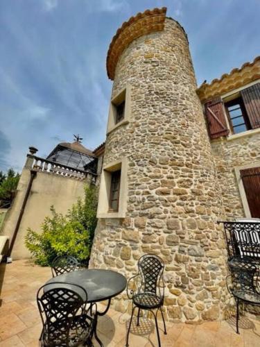 - un bâtiment en pierre avec une table et des chaises devant dans l'établissement Le Petit Château de Tournissan, à Tournissan