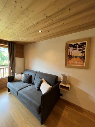 a living room with a blue couch and wooden ceilings at Studio face aux pistes in Praz-sur-Arly