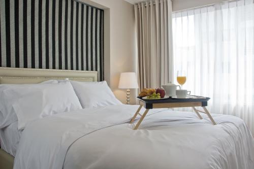 a white bed with a tray of fruit on it at Arvo Hotel Boutique in Trujillo