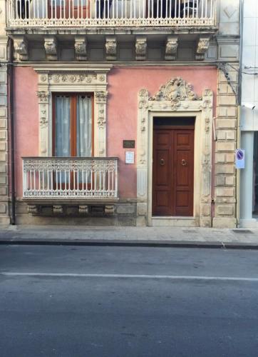 a building with a wooden door and a balcony at Vittorio Emanuele apartment in Canicattini Bagni
