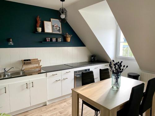 une cuisine avec des placards blancs et une table en bois dans l'établissement Appartement NATURA 2 chambres, à Vitré