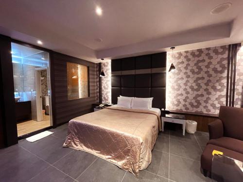 a bedroom with a bed and a chair and a window at King & Princess Motel - Rende in Rende
