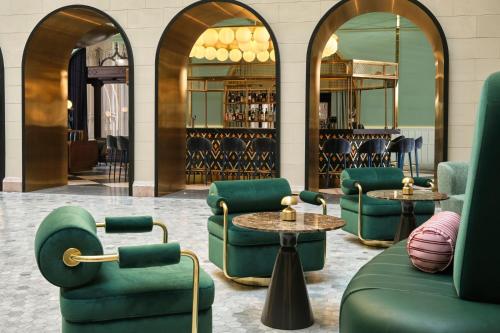 a lobby with green chairs and tables and mirrors at W Budapest in Budapest