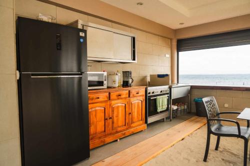 a kitchen with a black refrigerator and a table at Le Village de Vairao in Vairao
