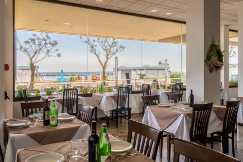a restaurant with tables and chairs with a view of the ocean at Hotel Eden in Bellaria-Igea Marina