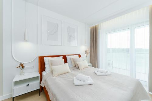 a white bedroom with a large bed with white pillows at Apartament z basenem Polanki Aqua D307 in Kołobrzeg