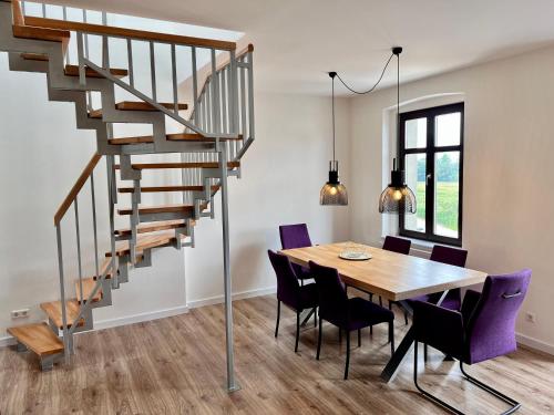 a dining room with a table and a spiral staircase at Apartment Kander 140 m2 mit Massagesessel in Görlitz