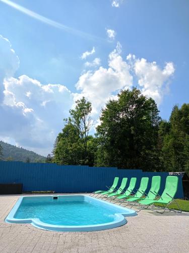 a swimming pool with chairs and a blue fence at Agroturystyka u Chlebków in Ochotnica Górna