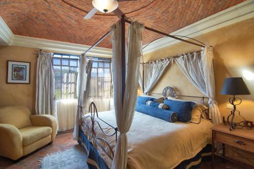 a bedroom with a canopy bed and a chair at Casa Puesta del Sol w/views slps 8 3 bths 3 bed in San Miguel de Allende