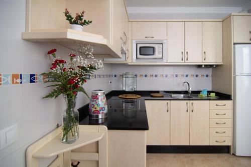 a kitchen with white cabinets and a vase of flowers at Casa Sun & Sea in Playa Honda